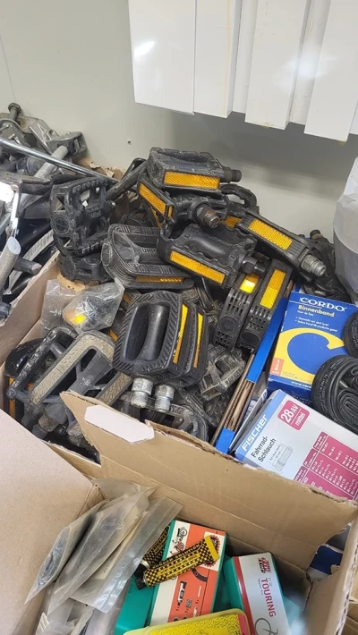 An open box filled with used bicycle pedals with reflectors.
